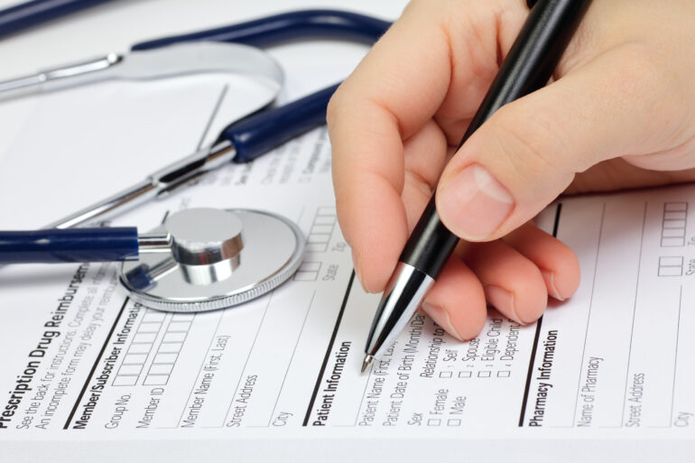 Hand with pen over blank form with patient information.