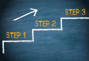 Three steps outlined on a chalkboard with Step 1, Step 2, and Step 3 above the outline and an arrow pointing up from Step 1 to Step 3.