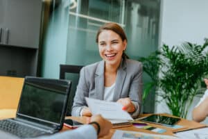 Board Certification: A woman smiles at a desk with a certificate in her hand.