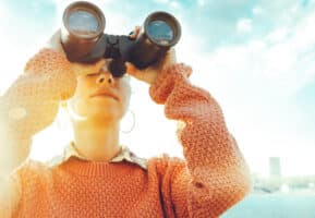 An internal medicine resident looking through binoculars to find the best internal medicine review course.