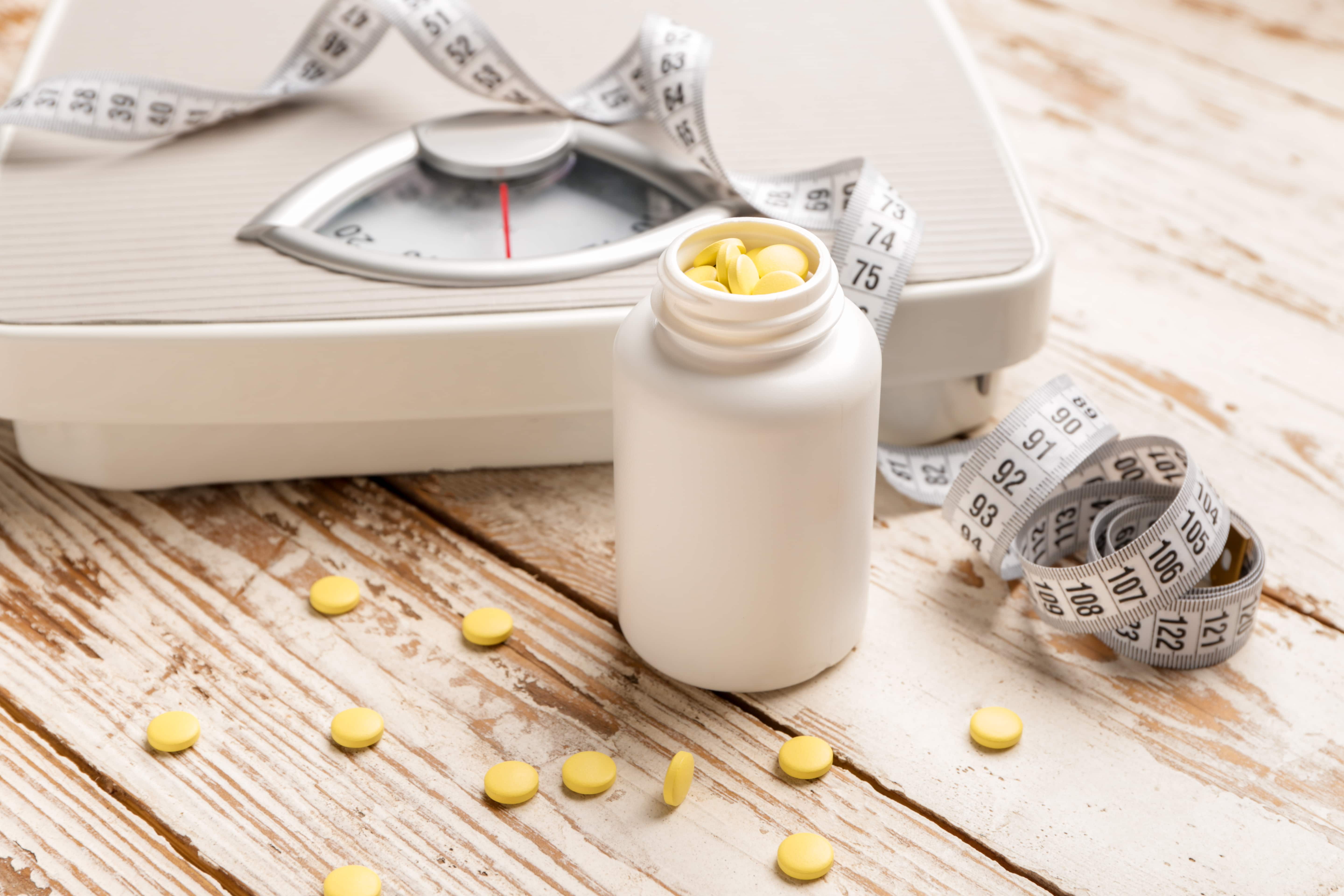 Scale with measuring tape and pills. Anti-obesity medications can help physicians create obesity treatment options.