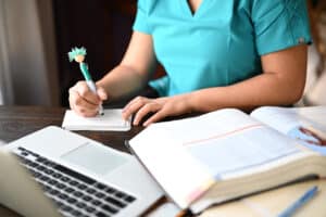 Medical student with textbooks, a laptop, and a board review course - how to study for the boards.