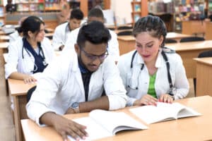 Two medical students at a desk with textbooks prepare for their ABIM cardiology boards.