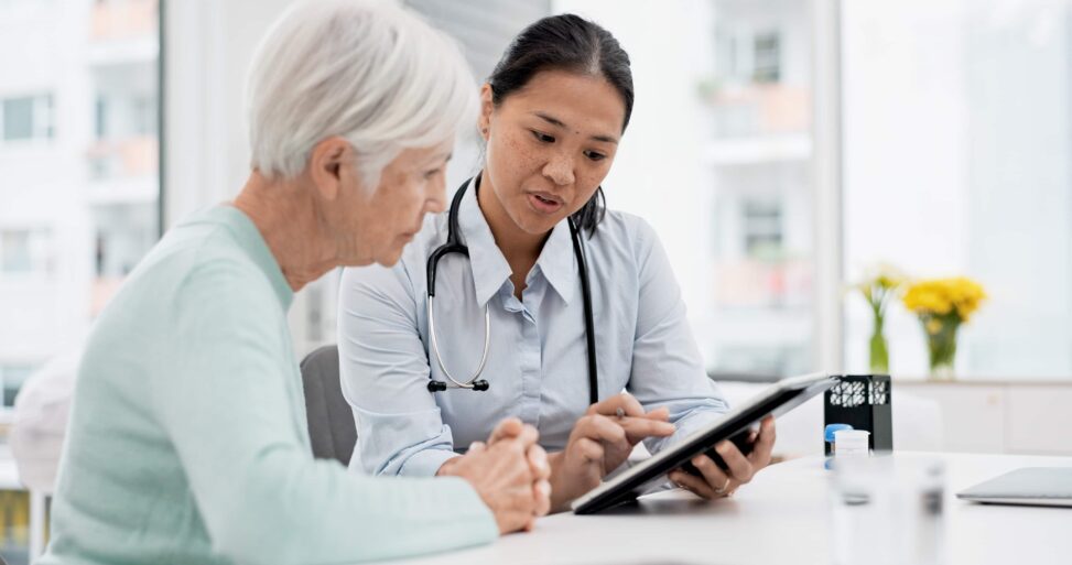 A geriatric medicine doctor explains treatment to her elderly patient