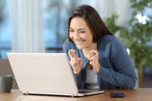 hopeful board exam student crossing fingers while checking board exam results on a laptop at home