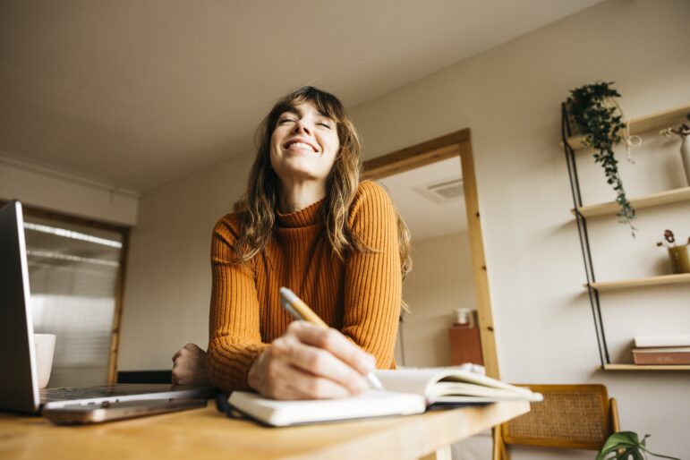 Physician studying at a desk and writing notes while preparing early for a board exam study plan.